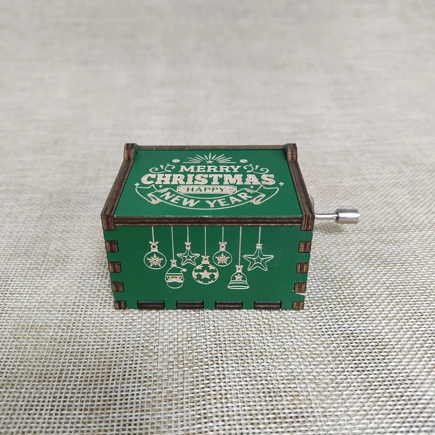 Open wooden Christmas music box with festive Merry Christmas artwork and visible hand-crank mechanism