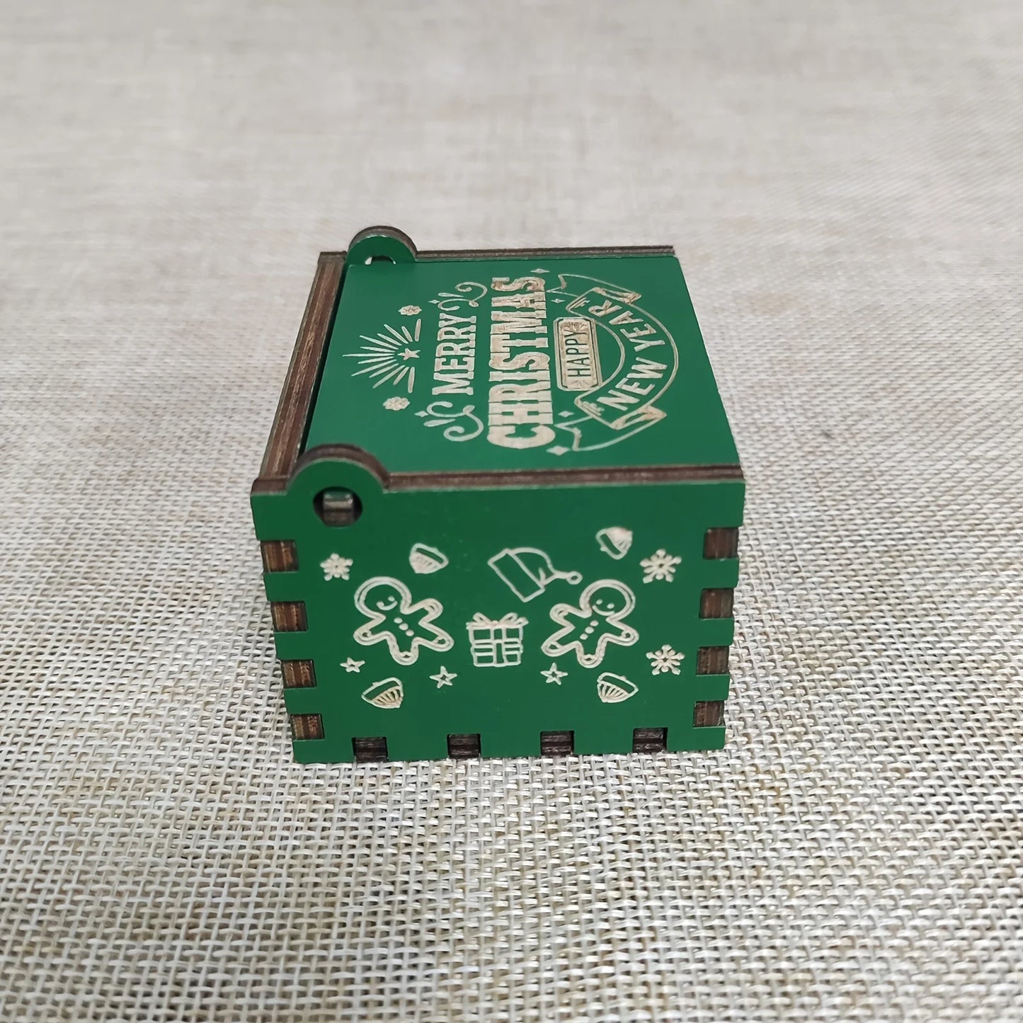 Green wooden box with Christmas-themed decorations on a textured fabric background