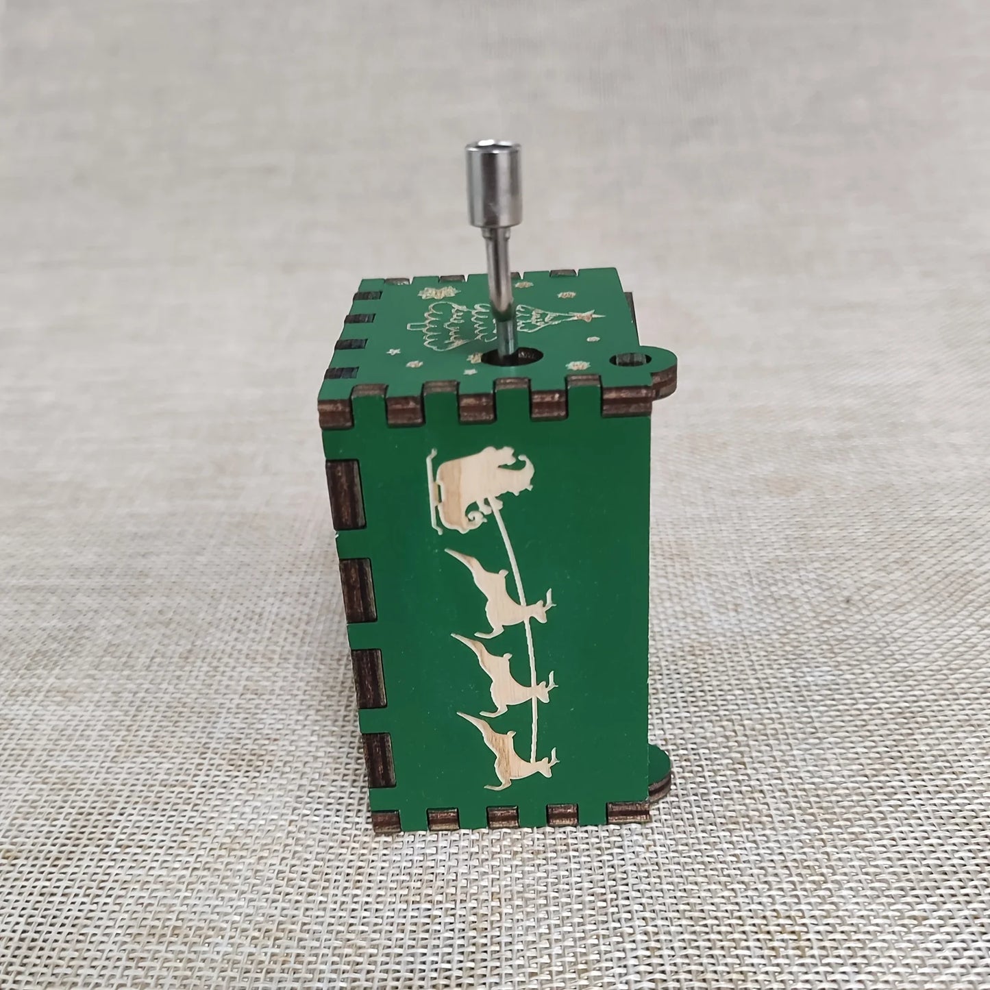 Green wooden music box with animal designs on a textured surface