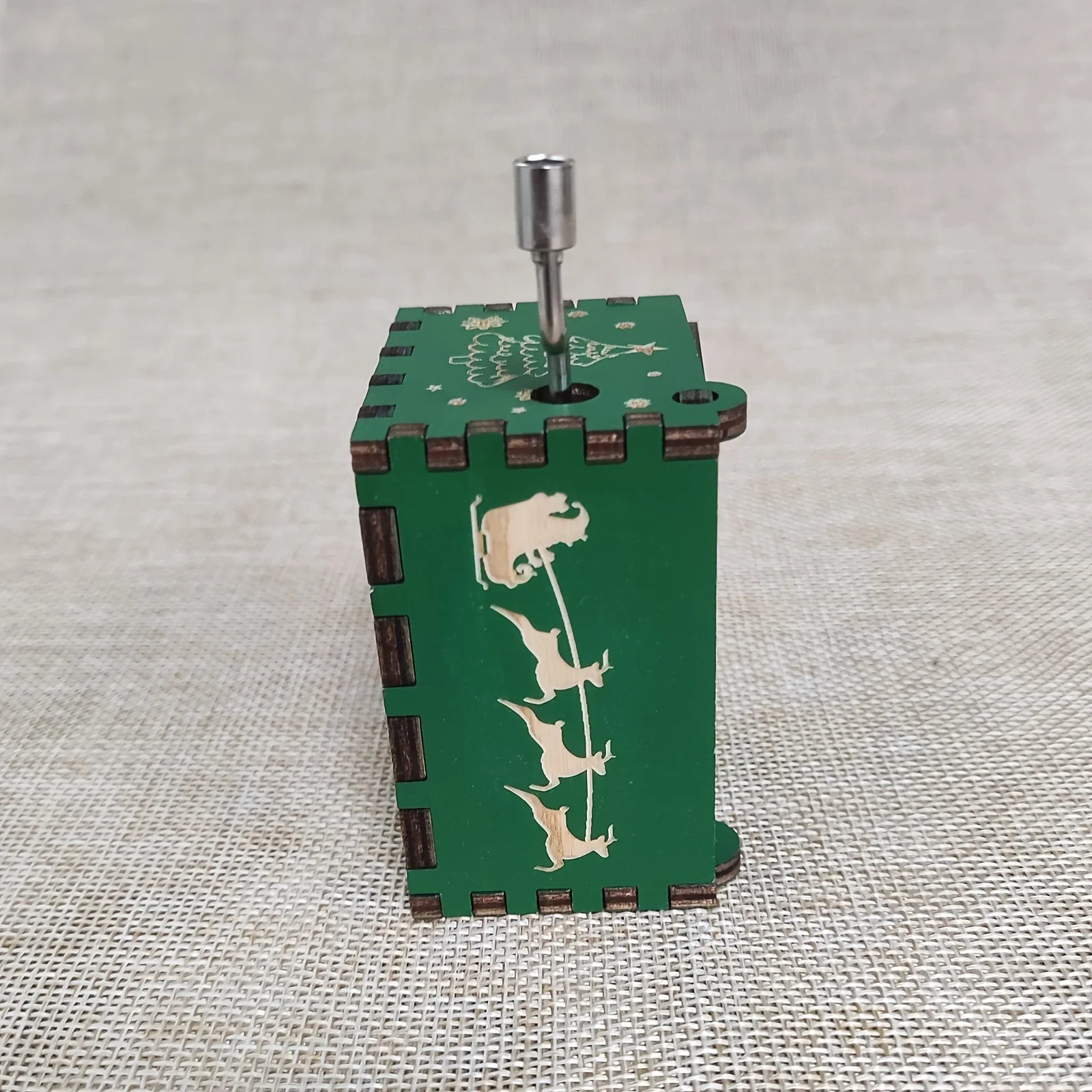 Green wooden music box with animal designs on a textured surface