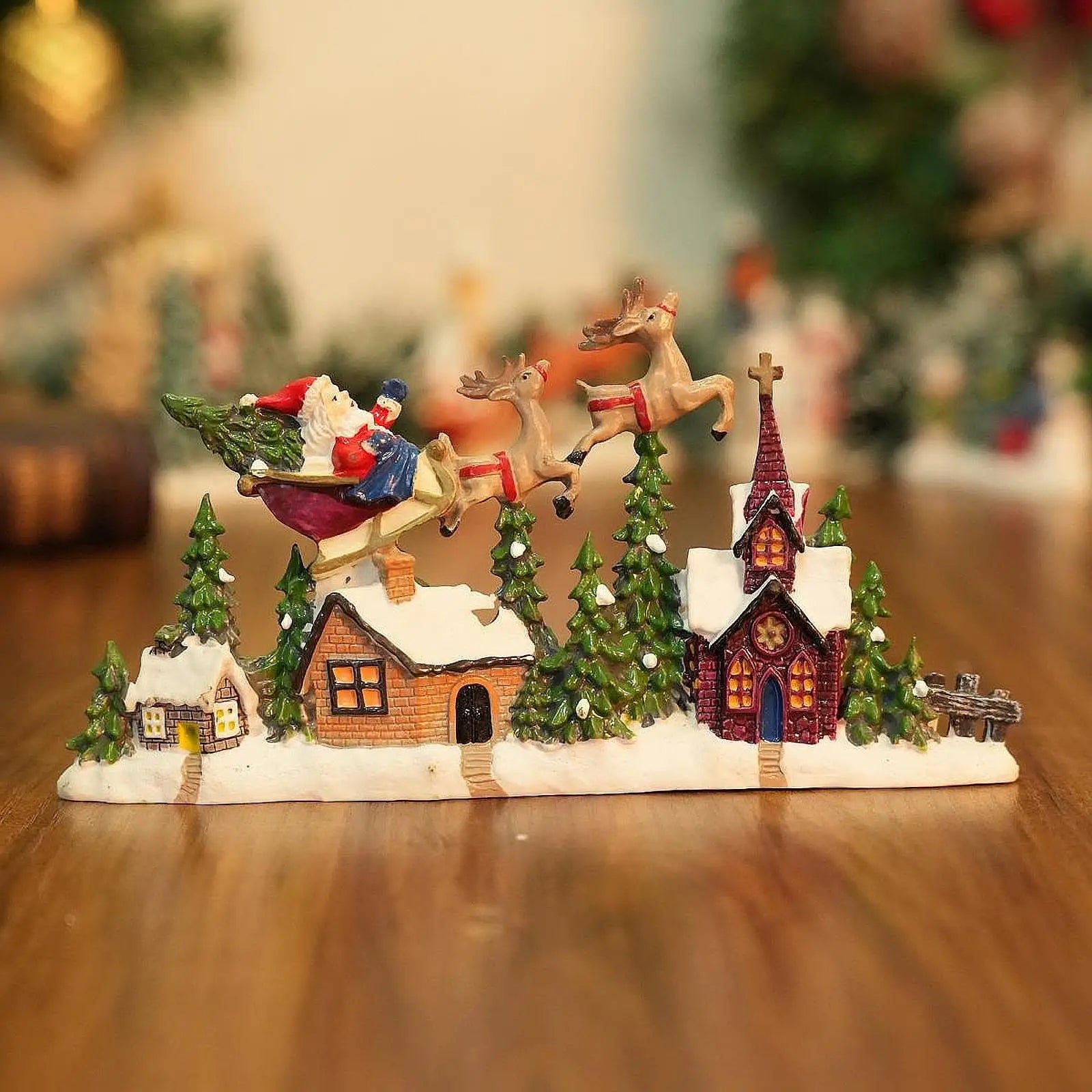 Christmas-themed miniature village scene with Santa Claus on a sleigh, reindeer, and houses.