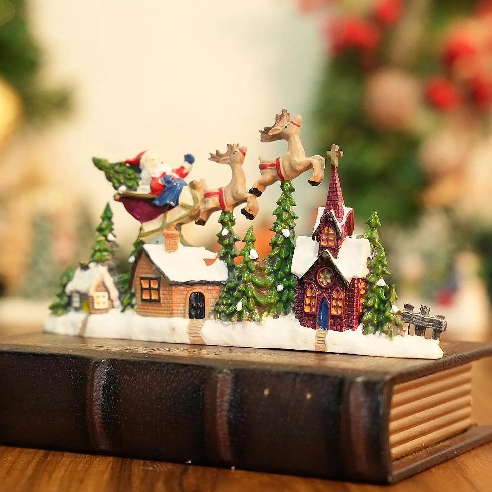 Christmas-themed miniature village scene with Santa Claus, reindeer, and houses on a book.